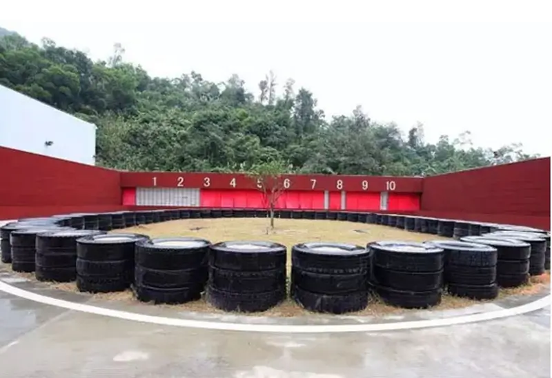 Outdoor shooting range featuring an enclosed Rubber Backstops and Traps design. The backstop uses a ballistic rubber curtain structure made of self-healing LINATEX natural rubber. Behind the ballistic curtain, a sealed space is used for bullet recovery. The design ensures easy maintenance, safety, and long lifespan.