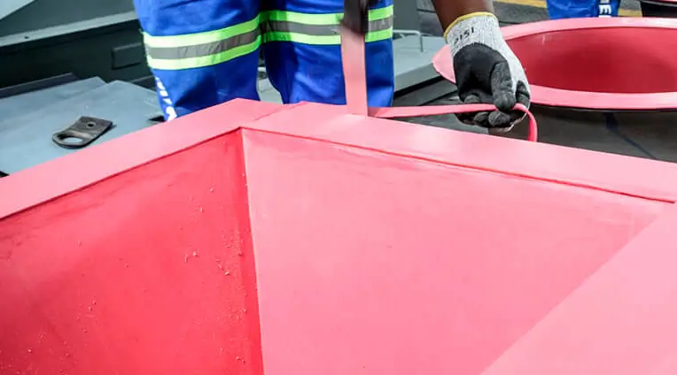 This photo shows the process of trimming excess rubber after the Linatex rubber lining has been bonded to the metal. This trimming work is done only after the rubber is fully adhered to the metal, cutting off any excess rubber at the edges.